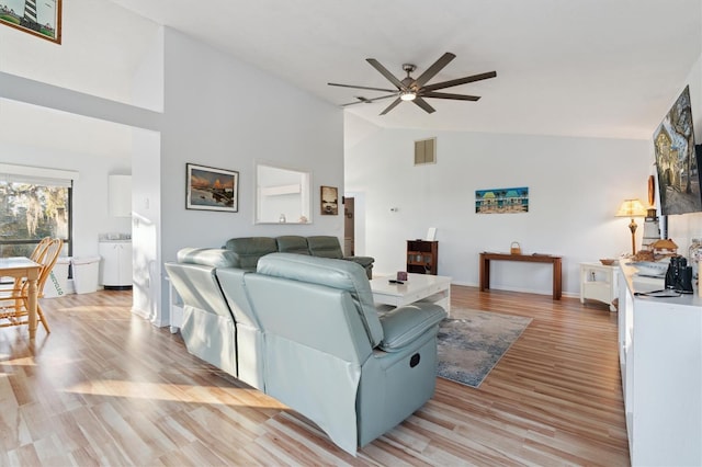 living room with ceiling fan, high vaulted ceiling, and light hardwood / wood-style floors