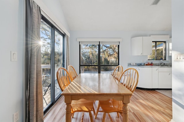 dining space with lofted ceiling, light wood-type flooring, and sink