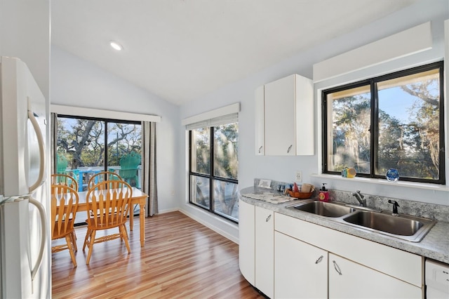 kitchen with white cabinetry, white appliances, lofted ceiling, light hardwood / wood-style flooring, and sink