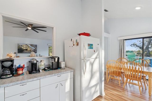 kitchen with a wealth of natural light, white refrigerator, lofted ceiling, and white cabinetry