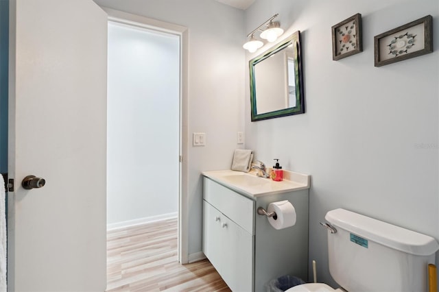 bathroom with toilet, vanity, and wood-type flooring