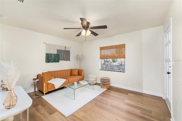 living area featuring wood finished floors, a ceiling fan, and baseboards