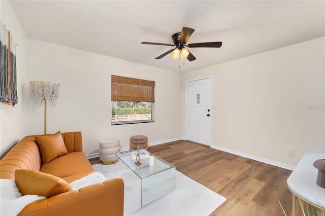 living area with wood finished floors, a ceiling fan, and baseboards