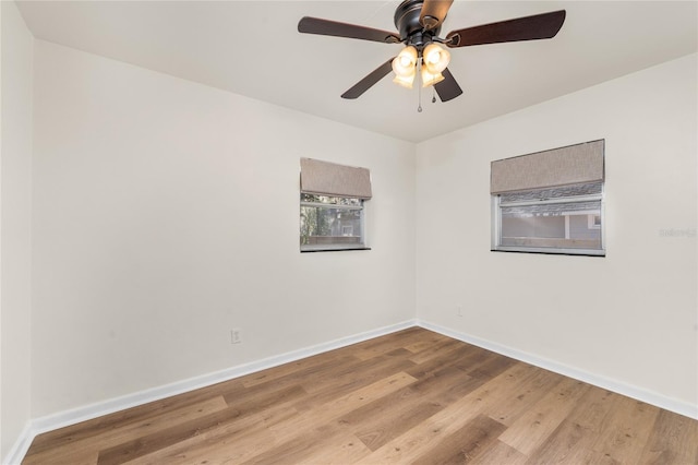 empty room with wood finished floors, a ceiling fan, and baseboards