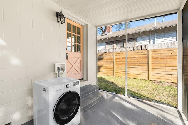 laundry area featuring concrete block wall, washer / dryer, and laundry area