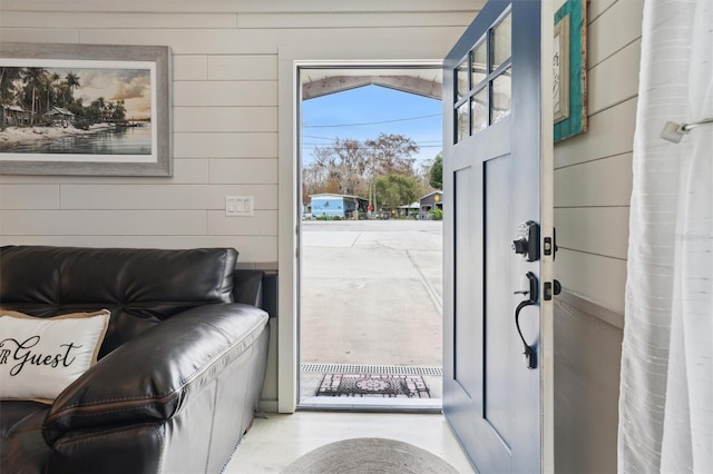 entryway with wooden walls and concrete floors