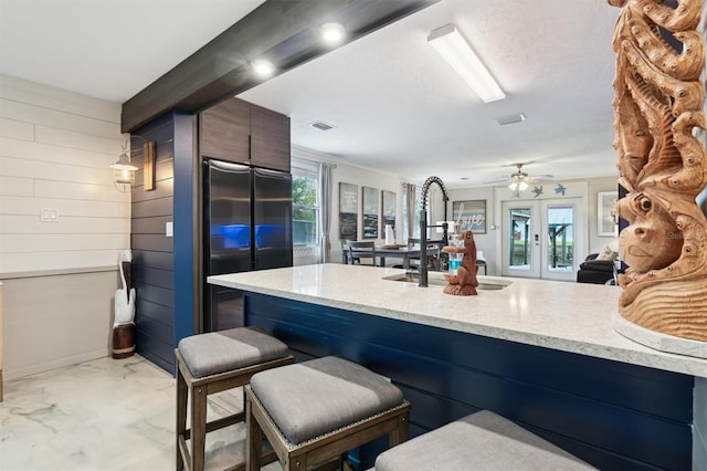 kitchen featuring sink, high quality fridge, a wealth of natural light, and wooden walls