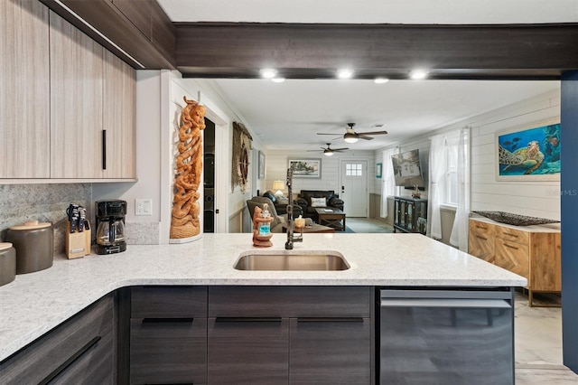 kitchen with kitchen peninsula, sink, light stone counters, and dark brown cabinetry