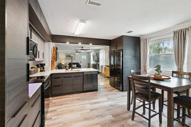 kitchen featuring black appliances, kitchen peninsula, light wood-type flooring, ceiling fan, and dark brown cabinets