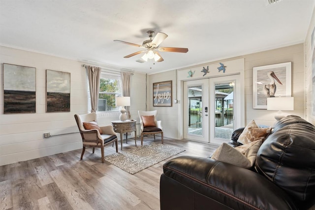 living area with french doors, ceiling fan, ornamental molding, and light hardwood / wood-style flooring