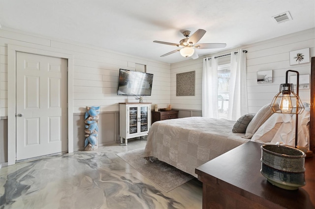 bedroom featuring ceiling fan and wooden walls