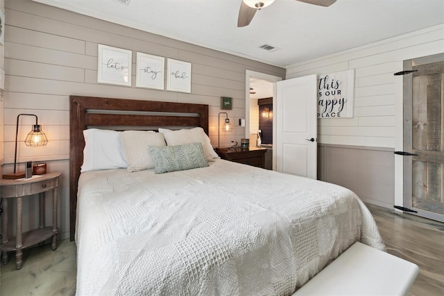 bedroom featuring ceiling fan, wooden walls, and concrete flooring