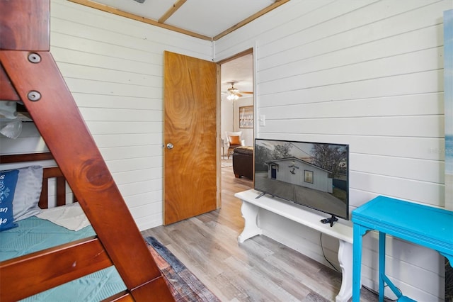 misc room featuring ceiling fan, wooden walls, and light hardwood / wood-style floors