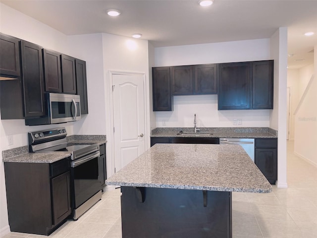 kitchen featuring a center island, a kitchen bar, sink, light tile patterned flooring, and appliances with stainless steel finishes