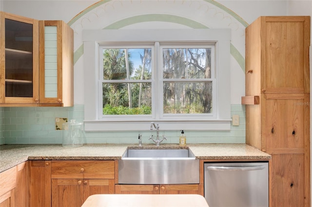 kitchen featuring decorative backsplash, sink, stainless steel dishwasher, and light stone countertops