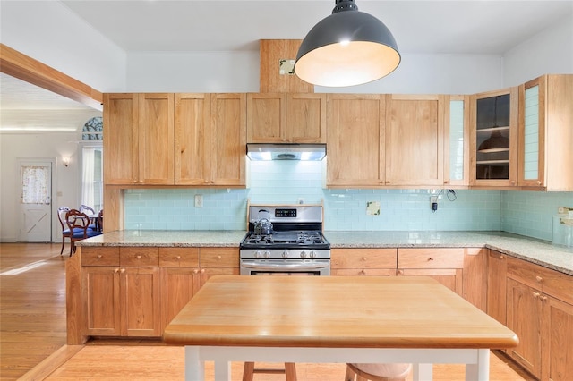 kitchen featuring tasteful backsplash, gas range, light stone counters, and pendant lighting