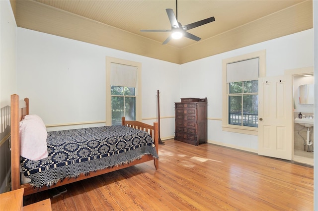 bedroom with ceiling fan, multiple windows, connected bathroom, and hardwood / wood-style floors