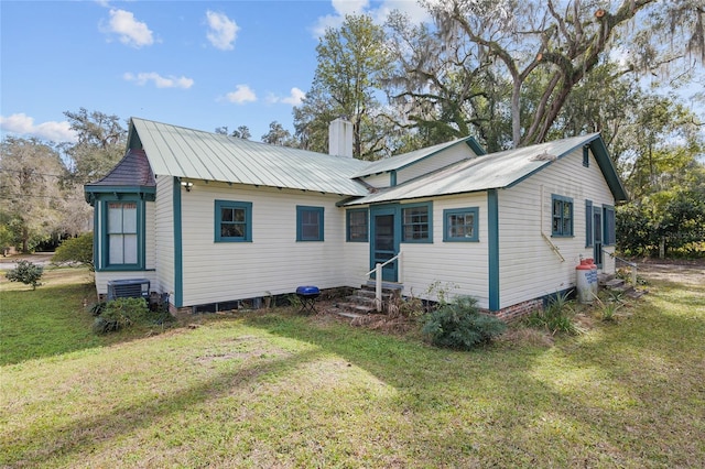 rear view of house with central AC unit and a yard