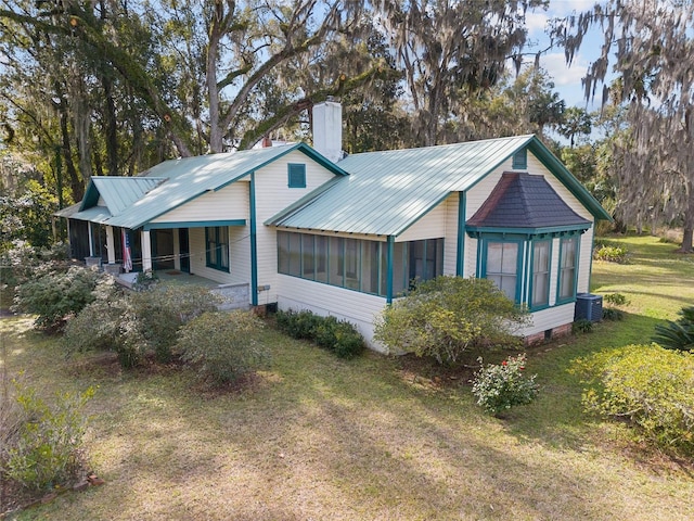 view of home's exterior featuring central AC unit, a sunroom, and a yard