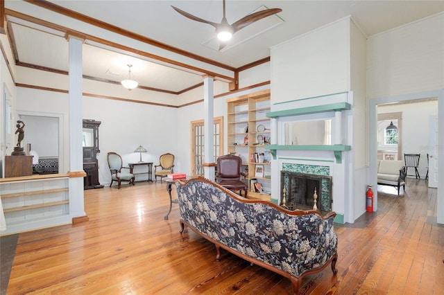 living room with a premium fireplace, ornamental molding, hardwood / wood-style floors, and ceiling fan