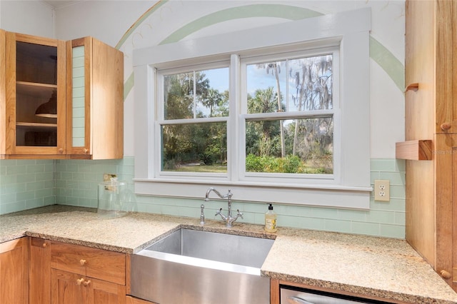 kitchen with dishwasher, decorative backsplash, light stone countertops, and sink