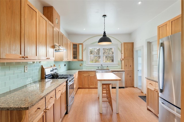 kitchen with light stone counters, pendant lighting, appliances with stainless steel finishes, and light wood-type flooring