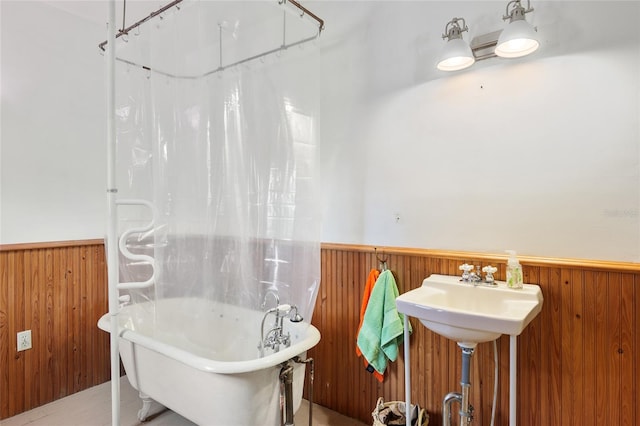 bathroom with a tub and wood walls