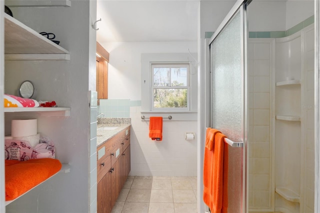 bathroom featuring a shower with shower door, tile walls, vanity, and tile patterned flooring