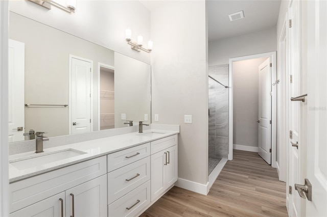 bathroom with hardwood / wood-style floors, vanity, and a tile shower