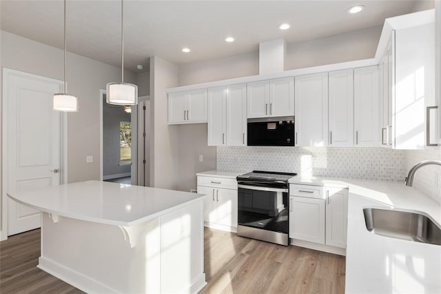 kitchen with a kitchen island, stainless steel electric stove, white cabinetry, and sink