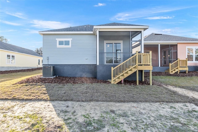 rear view of house with central AC and a sunroom