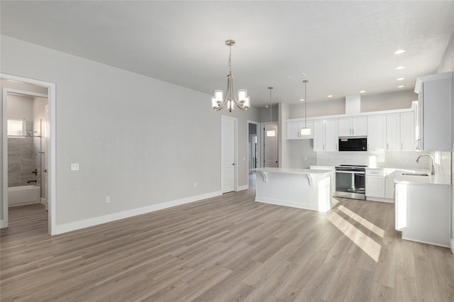 kitchen with white cabinets, a kitchen island, decorative light fixtures, tasteful backsplash, and electric range