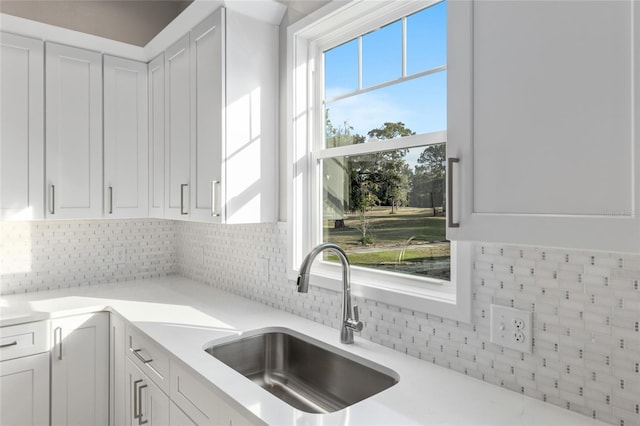 kitchen with white cabinets, backsplash, and sink