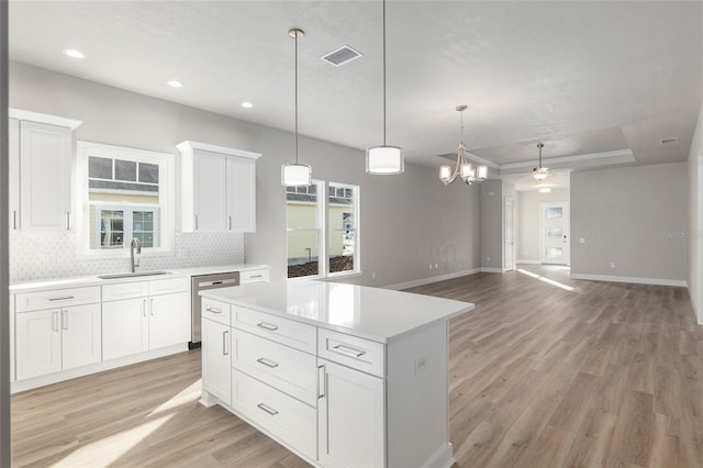 kitchen with white cabinetry, decorative light fixtures, sink, stainless steel dishwasher, and a center island