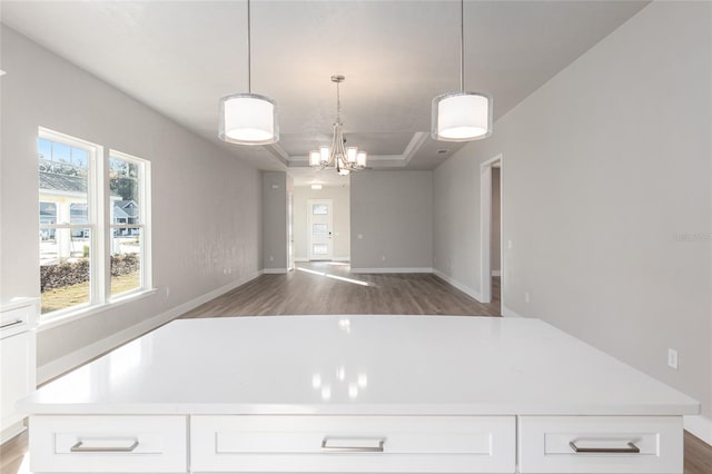 kitchen with white cabinetry, a tray ceiling, dark hardwood / wood-style flooring, and hanging light fixtures