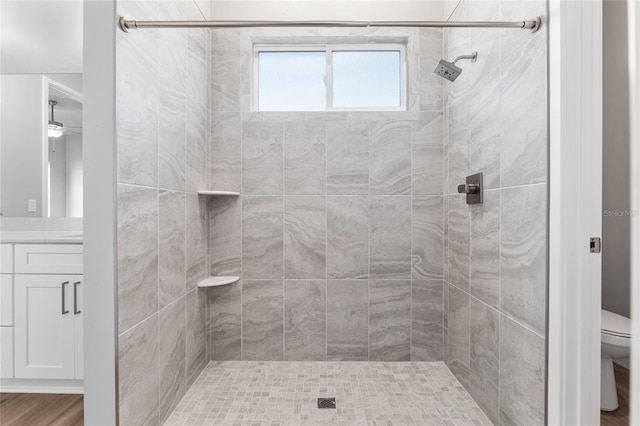 bathroom featuring toilet, a tile shower, and vanity