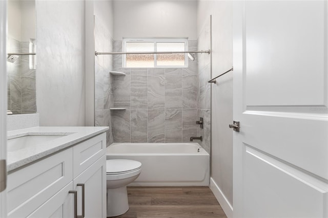 full bathroom with toilet, vanity, tiled shower / bath combo, and hardwood / wood-style flooring