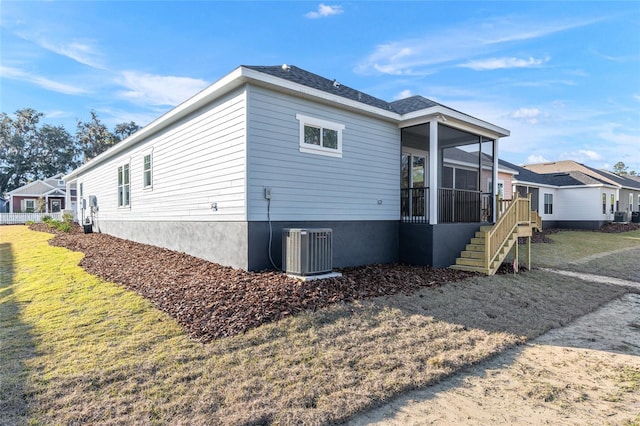 view of home's exterior featuring a sunroom, a yard, and central AC