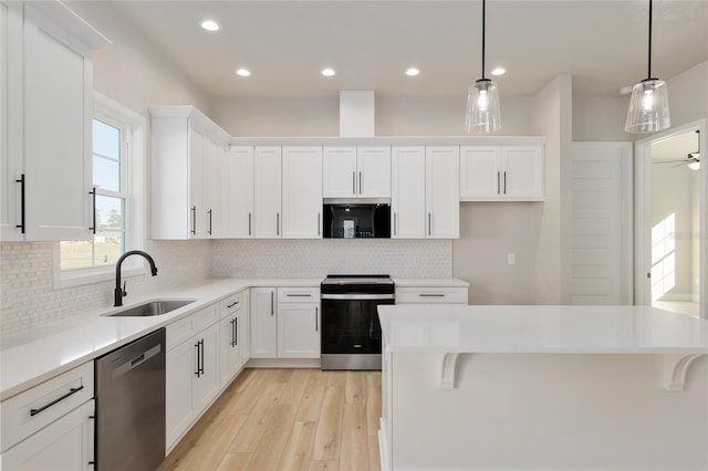 kitchen with sink, appliances with stainless steel finishes, white cabinetry, light hardwood / wood-style floors, and decorative light fixtures