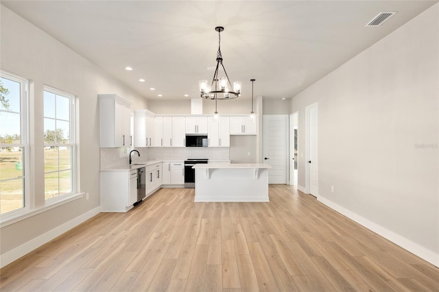 kitchen with sink, stove, backsplash, white cabinets, and a kitchen island