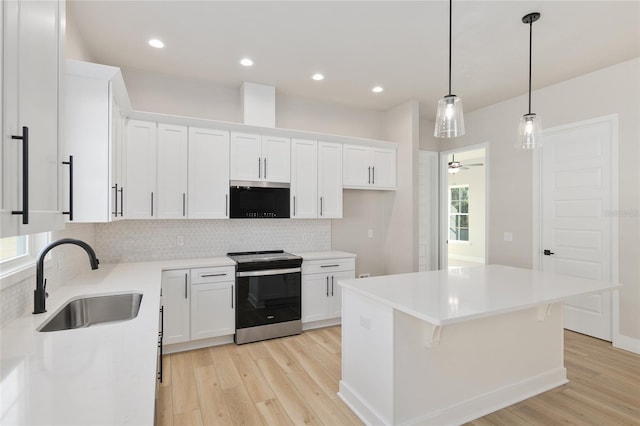 kitchen featuring stainless steel electric range oven, a center island, sink, and white cabinets