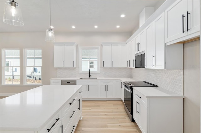 kitchen featuring pendant lighting, sink, electric range, tasteful backsplash, and white cabinets