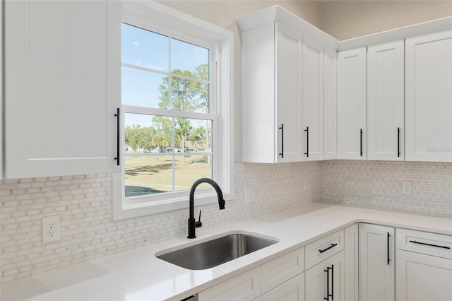 kitchen featuring white cabinetry, sink, and backsplash