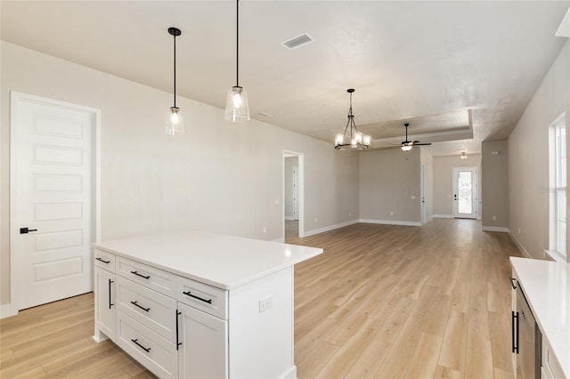 kitchen featuring light hardwood / wood-style floors, a kitchen island, pendant lighting, ceiling fan with notable chandelier, and white cabinets