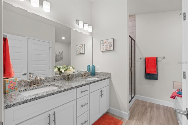 bathroom featuring a shower with shower door, vanity, and wood-type flooring