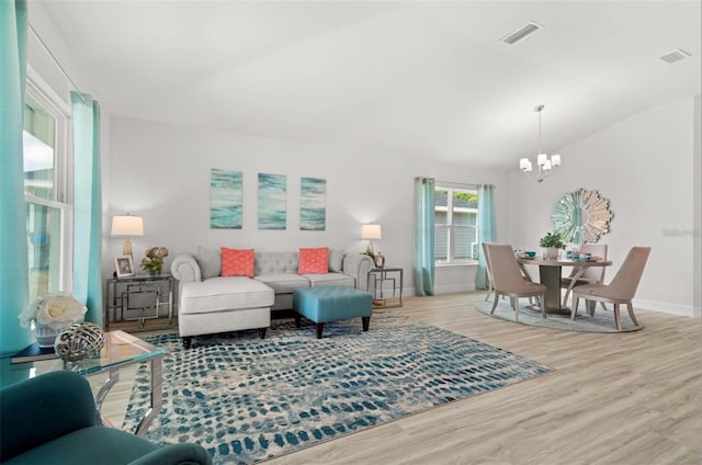 living room featuring vaulted ceiling, a chandelier, and light hardwood / wood-style flooring