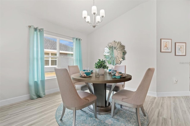 dining room with light wood-type flooring, vaulted ceiling, and a chandelier