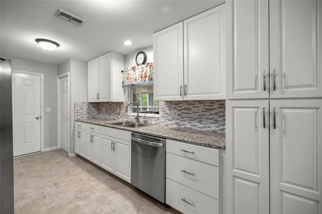 kitchen featuring dark stone countertops, stainless steel dishwasher, decorative backsplash, sink, and white cabinets