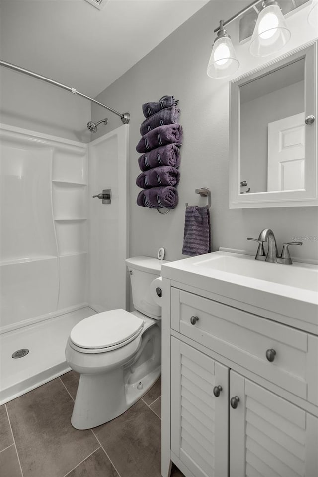 bathroom featuring toilet, tile patterned flooring, a shower, and vanity