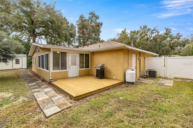 back of house with a lawn, cooling unit, an outbuilding, and a wooden deck